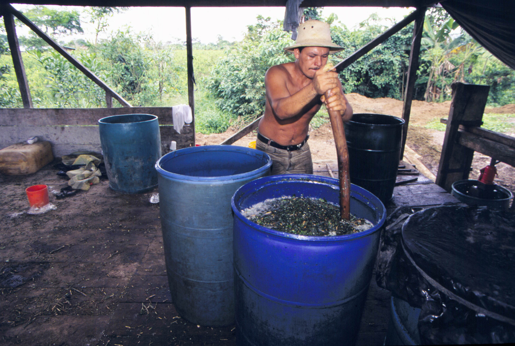 man stirring barrel of coca plant, making cocaine