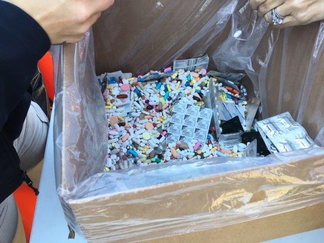 A brown box lined with a plastic bag holds several medications.
