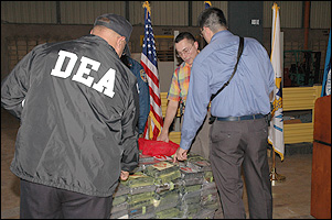 DEA agent inspects distinctive markings on seized cocaine.