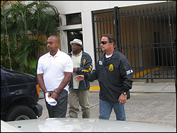 A DEA Special Agent and a Deputy U.S. Marshal escort VIPD Captain Enrique Saldana. 