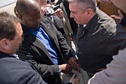 Ze'ev Rosenstein (right) is escorted by federal agents as he boards a plane bound for the United States.