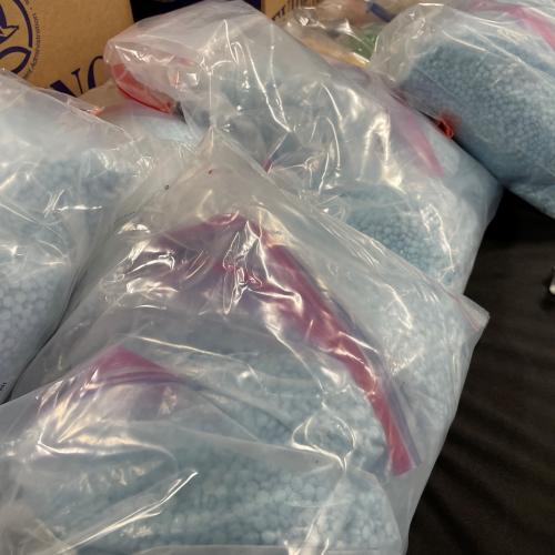 Bags of blue fentanyl pills, displayed on a table top
