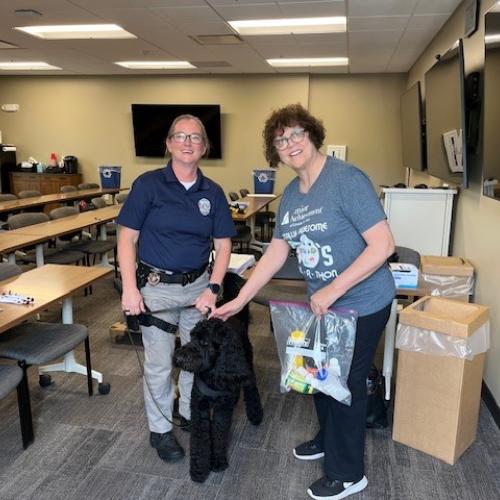 Two people and a dog stand next to a Take Back Day location.