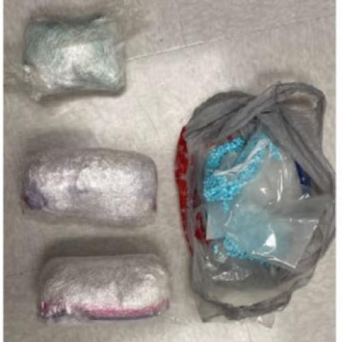 Photo of three packages of meth and multiple packages of blue fentanyl pills seized in March 2023.