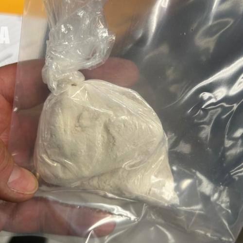 a hand holding a baggie of powder