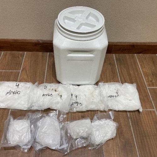 A white bucket with several packages containing a white substance in front of it.