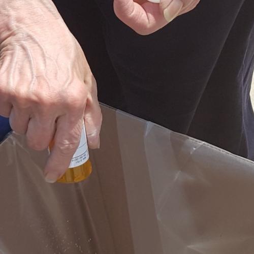 National Prescription Take Back Day collection site photo showing an individual emptying prescription medications into a large brown box.