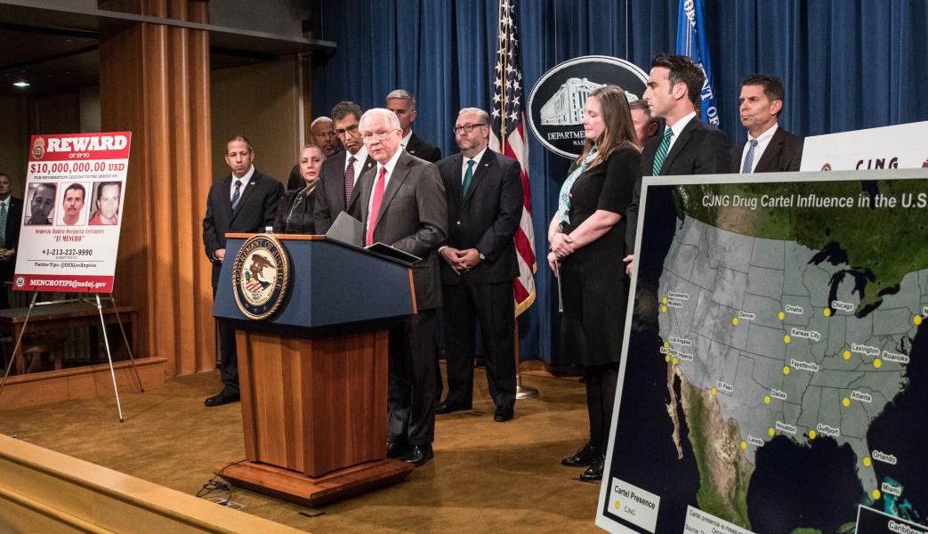 AG Session at podium with map of the US and other officials
