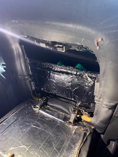 Seized money wrapped and packaged, located within a hidden compartment of a vehicle.