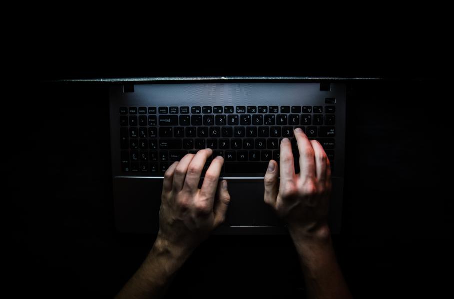hands typing on a computer keyboard in the dark