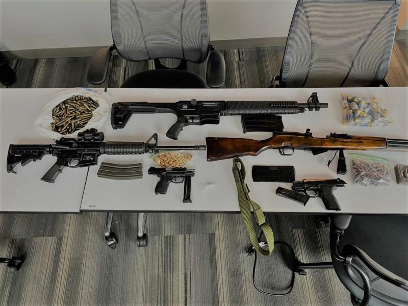 Photograph of assualt weapons arranged on a table that were seized from one trafficker.