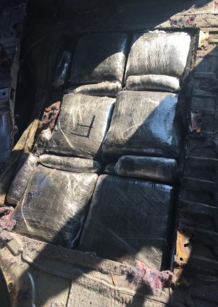 Photo of hidden compartment within a vehicle containing 21 packages of fake M30 fentanyl pills.