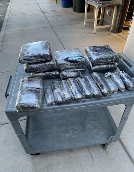 Photo of multiple packages containing fake fentanyl pills  (one package opened, blue pills visible) found inside a vehicle concealed compartment. 