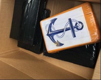 Photo of kilograms of seized controlled substance.  Three of the kilograms are wrapped in black.  One kilogram wrapped in brown with a blue anchor logo