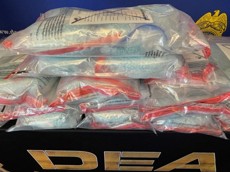 Bags of fentanyl pills displayed on a table, with DEA banner below