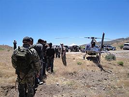 Detainees arrested at the grow site were led by law enforcement officers to vehicles for transport out of the rugged area. 