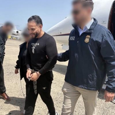 Photo of Mosquea Polanco (left of center) surrounded by law enforcement after being extradited from Colombia to the United States.