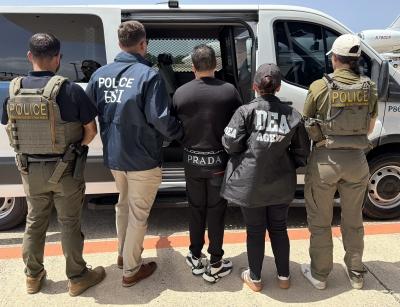Photo of Mosquea Polanco (center) surrounded by law enforcement after being extradited from Colombia to the United States.